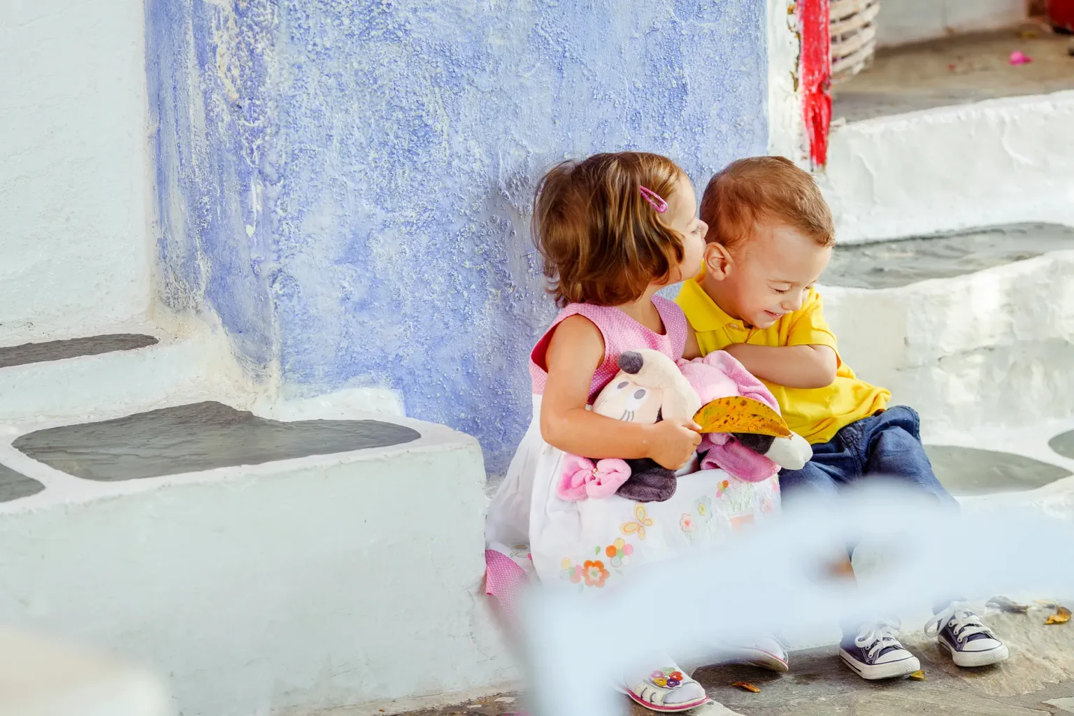 a boy and girl sitting on steps and kissing each other